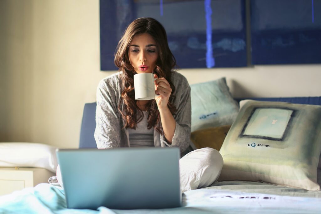 Work from Home Woman sitting on bed with coffee computer