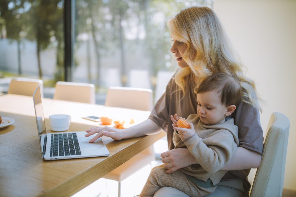 Woman Working and Holding her baby at a table at work from home