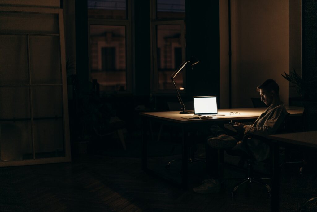 man sitting in the dark while working on the computer