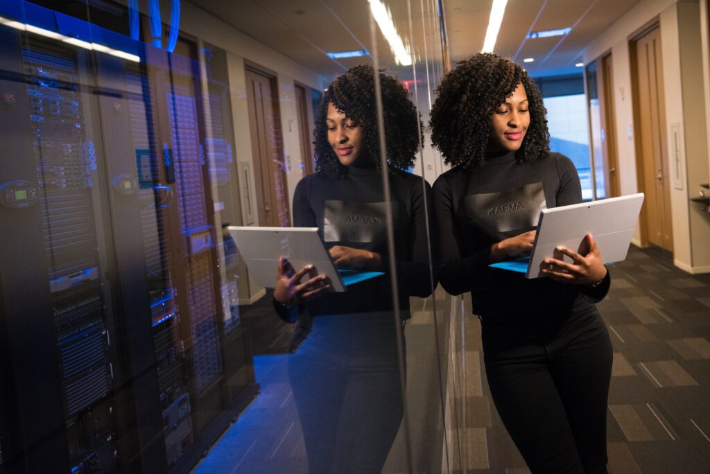 Woman working on a laptop while leaning against a glass wall passion work