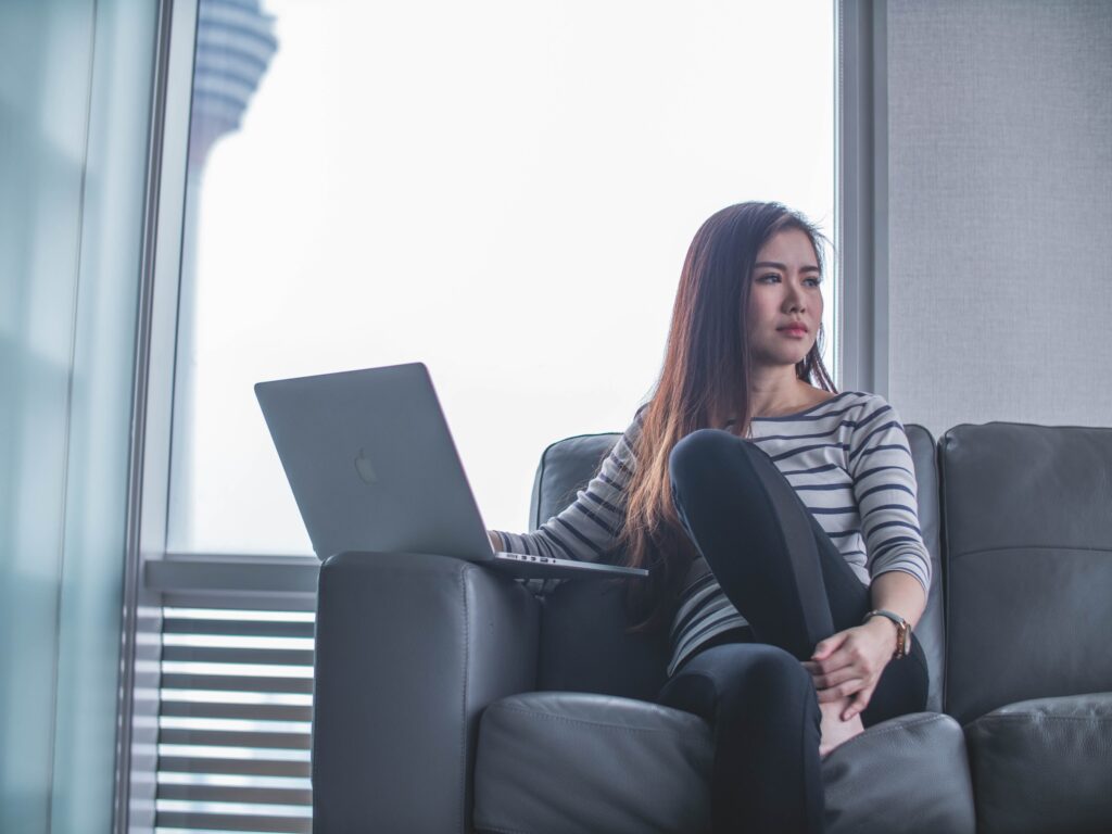 Woman Sitting on Couch Staring Off on Laptop Career Coaching