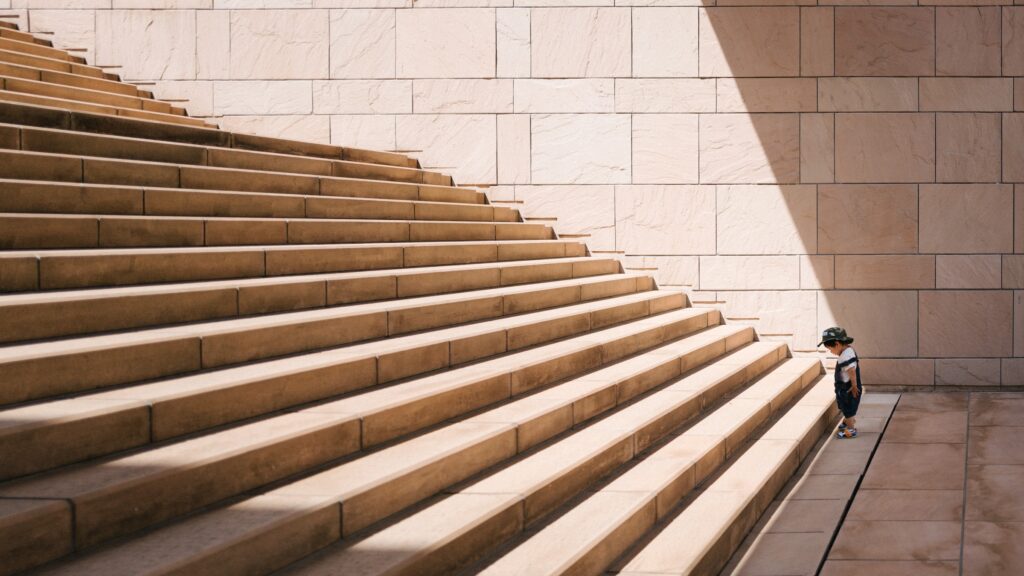 child standing at the bottom of a large staircase